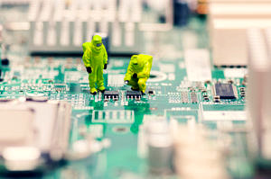 Kleine Figuren im Schutzanzug stehen auf einem gigantischen Chip.